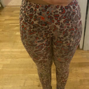 Leopardmönstrade leggings i brunt och rött - Säljer ett par tajta leggings med leopardmönster i bruna och röda toner. Byxorna har hög midja och är stretchiga. I den bakre sidan är materialet nästan som skinn byxor. Står ingen strl men gissar på Xs-S