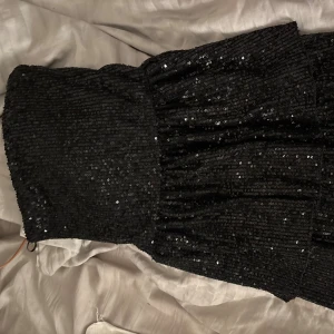 Svart paljettklänning Gina Tricot - Säljer en svart, glittrig kortklänning från Gina Tricot. Klänningen är täckt av paljetter och har en figurnära passform utan axelband. Perfekt för dig som vill sticka ut med en snygg och festlig look. Perfekt på nyår!🤍