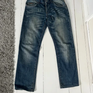 Blå jeans från D&G med broderi - Snygga blå jeans från D&G med coolt gult broderi på bakfickorna och slitna detaljer framtill. Klassisk femficksmodell med raka ben och normal passform. Jeansen har en faded effekt och är tillverkade i robust denim för en streetig look. Självklart äkta som alla andra varor🤩🤩