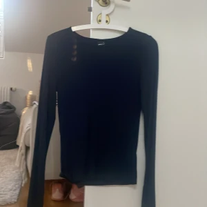 Svart långärmad topp från Gina Tricot - En stilren svart långärmad topp från Gina Tricot. Modellen är figurnära med rund halsringning och enkel design, perfekt att matcha med allt. Tunn och mjuk i materialet, passar året runt.