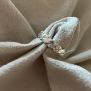 Ring - Säljer en snygg ring i silver med flätad struktur runt hela ringen. Den har en blank finish och passar perfekt för dig som gillar minimalistiska och trendiga smycken. Ringen är rund och har en cool twistad look som gör den unik.