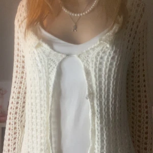 Vit virkad kofta med öppen front - Säljer en superfin vit virkad kofta med öppen front och lång ärm. Koftan är stickad i ett luftigt mönster och passar perfekt att slänga över ett linne eller t-shirt. Enkel och stilren design som ger en fräsch look. Perfekt till stranden eller somriga kvällar.