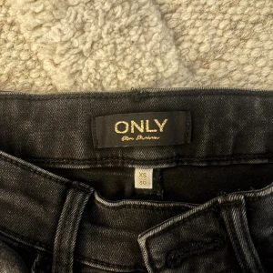 Svarta bootcut jeans från ONLY XS - Snygga svarta jeans från ONLY i storlek XS med bootcut passform. Jeansen har klassisk femficksdesign, knapp och dragkedja fram samt lätt tvättad look. Perfekta för dig som gillar en lite vidare siluett nedtill och vill ha en cool stil. Tveka inte på att höra av dig vid frågor eller intresse!