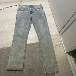 True Religion Ricky ljusblå jeans  - Ljusblå jeans från True Religion, modell Ricky Relaxed Straight. Klassisk femficksdesign med tydliga sömmar och ikoniska bakfickor med lock och broderi. Jeansen har rak passform och är tillverkade i denim med en tvättad look.