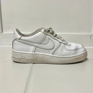Nike Air Force 1 vita sneakers 37,5 - Klassiska Nike Air Force 1 sneakers i helvitt skinn med perforerad tå, snörning och låg profil. Swoosh-logga på sidorna och Nike Air-brodyr på hälen. Perfekta för dig som gillar en clean och tidlös look. (Storlek 37,5 Unisex) Pris kan diskuteras.