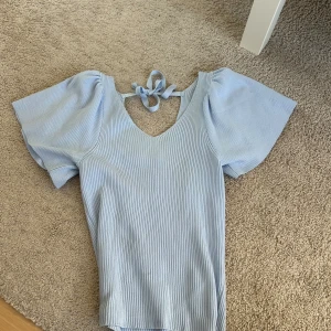 Ljusblå ribbad topp med puffärm - Supersöt ljusblå topp. Toppen en rosett i ryggen.