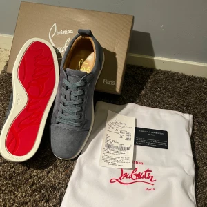 Christian Louboutin blå  mockasneakers - Snygga sneakers från Christian Louboutin i blå mocka med klassisk röd sula och vita kanter. Skorna har rund tå, snörning och diskreta ventilationshål på sidan. Insidan är fodrad i beige läder och märket syns tydligt på sulan och innersulan.