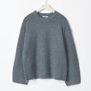 Grå stickad tröja från Gina  - Mysig grå stickad tröja från Gina tricot  med rund halsringning och långa ärmar. Tröjan har en loose passform och ribbade muddar vid ärmslut och nederkant. Perfekt för kyliga dagar och enkel att styla med jeans eller kjol.