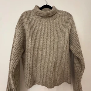 Beige stickad polotröja Gina Tricot - Mysig beige stickad polotröja från Gina Tricot i storlek XXS. Tröjan har grov ribbstickning, hög krage och långa ärmar. Perfekt för dig som gillar en enkel och chill look med lite oversized känsla. Snygg att matcha med jeans eller kjol.
