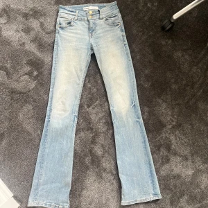 Lågmidjade ljusblå bootcut jeans från Bershka - Säljer ett par snygga ljusblå jeans från Bershka med bootcut passform och låg midja. Jeansen har två knappar vid midjan. De är i storlek 34 alltså XS. Jag köpte de från en annan person på appen men har själv aldrig använt de💕💕