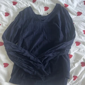 Mörkblå blus med v-ringning från Kaffe - Snygg mörkblå blus från Kaffe i storlek 34. Blusen har v-ringning, långa ärmar med lätt rynk vid ärmslut och är tillverkad i ett tunt, luftigt tyg. Perfekt för dig som gillar stilrena och enkla plagg med en klassisk touch.