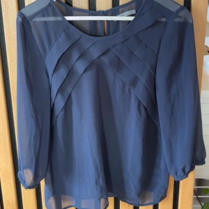 Blå transparent blus med veck - Säljer en blå blus i transparent material med snygga veckdetaljer framtill. 