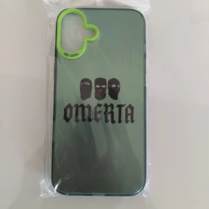 iPhone Omerta Skal - Snyggt och unikt Omerta-skal till iPhone, med motiv av tre maskerade ansikten och texten 'OMERTA'. Skalets kant är grön med texten 'SO COOL'. Produkten är ny och ligger i originalförpackning, utan synligt slitage eller defekter.