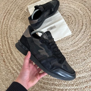 Valentino Rockrunner - Valentino Rockrunner sneakers i svart och grått med kamouflagemönster. Skorna har detaljer i mocka och skinn, klassisk snörning och ikoniska nitar på hälen. Storlek 41,5 true to size. Nypris på dessa är 8500kr