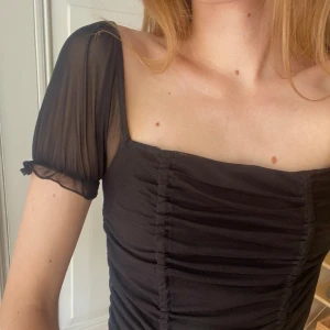 Svart mesh topp Urban Outfitters  - Svart mesh topp från Urban Outfitters. Fyrkantig urringning och genomskinliga korta ärmar.