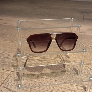 Bruna fyrkantiga solglasögon - Snygga solglasögon med brun fyrkantig båge och tonade glas. De har en cool metall-detalj upptill och klassisk retrostil. Perfekta för att lyfta din look med en vintagevibe. Passar dig som gillar statement-accessoarer.