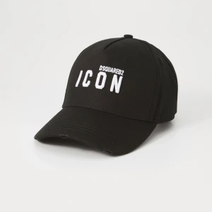 Svart keps DSQUARED2 ICON - Svart keps från DSQUARED2 med stor vit broderad text 'ICON' framtill och mindre DSQUARED2-logga ovanför. Klassisk böjd skärm och justerbar passform. Tillverkad i bomull och har en stilren, urban look som sticker ut. Hjälper min bror sälja denna kepsen, originalpris: 1445kr. Kepsen är lite dammig men väldigt enkelt att bara putsa bort, annars är kepsen i jättebra skick. Pris kan diskuteras vid snabbt köp
