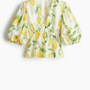 Citronmönstrad blus med puffärm - Superfin blus med citronmönster i gult och grönt på vit botten. Blusen har v-ringning, smockad midja och puffiga trekvartsärmar med resår. Perfekt för dig som vill sticka ut med en färgglad och somrig vibe! Använd få gånger 