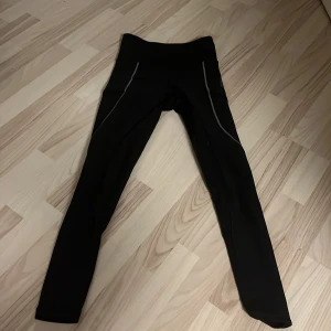 Svarta ridleggings Maya Delorez S - Svarta ridleggings från Maya Delorez i storlek S. De har hög midja, gråa detaljer längs benen och logga på höften. Tillverkade i stretchigt syntetmaterial som sitter tight och bekvämt. Säljer dessa då jag ej rider längre.