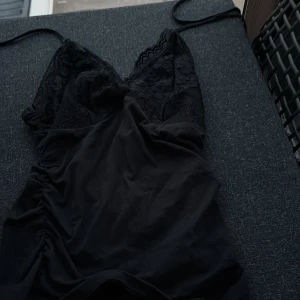 Svart spetslinne med smala band - Supersnygg svart linne med smala axelband och spetsdetaljer upptill. V-ringad och figurnära modell som ger en elegant look. 🖤