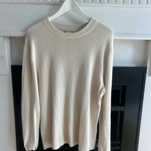Beige stickad tröja från Zara - Snygg beige stickad tröja från Zara i storlek M. Tröjan har rund hals med ribbad kant och långa ärmar. Materialet är mjukt och skönt, perfekt för lager på lager. Enkel och stilren design som funkar till många olika looks.
