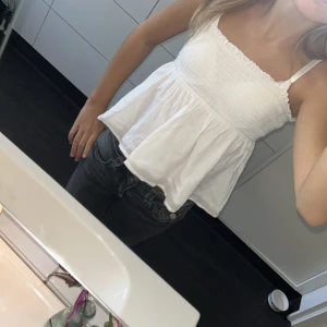 Vit smockad linnetopp Gina Tricot - Supersöt vit linnetopp från Gina Tricot med smockad överdel och volangig nederdel. Toppen har tunna axelband och en luftig, flowy passform som är perfekt för varma dagar. Materialet är mjukt och lätt bomull, vilket gör den skön att bära hela sommaren. Dock så är båda snörena borttappade 💕