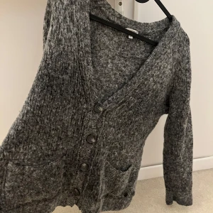 Grå kofta från Better Rich, storlek S - Mysig grå kofta från Better Rich i stickad ullmix. Koftan har v-ringning, knappar framtill och två praktiska fickor. Perfekt för lager-på-lager. Långärmad och loose fit. Tröjan är endast använd 2 gånger 💕