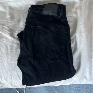 Svarta jeans från 157, rak modell - Svarta jeans från 157 med klassisk femficksdesign och dragkedja. Jeansen har raka ben och normal passform, tillverkade i ett mjukt bomullstyg. Perfekta för dig som gillar en enkel och stilren look.