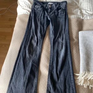 Svarta bootcut jeans från Gina Tricot - Snygga svarta jeans från Gina Tricot i bootcut-modell. Jeansen har klassisk femficksdesign, silverfärgade knappar och kontrastsömmar. Perfekta för dig som gillar en tidlös look med lite utsvängda ben. Materialet är jeans i bomullsblandning.
