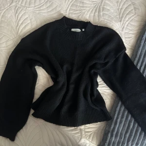 Svart stickad tröja från ADPT XL - En svart stickad tröja från ADPT i storlek XL. Tröjan har rund halsringning, ribbade muddar och är långärmad. Perfekt för dig som gillar en enkel och stilren look med lite loose fit.