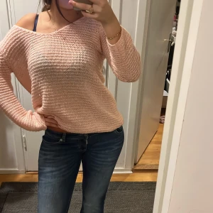 Ljusrosa stickad tröja - Säljer en ljusrosa stickad tröja med offshoulder-look och långärmade ärmar. Tröjan har en loose passform och är gjord i ett mjukt stickat material som känns chill och skönt. Perfekt att slänga på sig när du vill ha en avslappnad vibe.