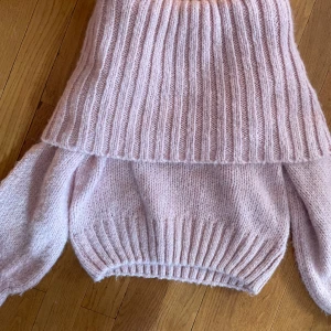 Ljusrosa stickad off shoulder tröja Gina Tricot - Supermysig ljusrosa stickad off shoulder tröja från Gina Tricot. Tröjan har en bred, ribbad polokrage och långa ärmar. Perfekt för lager-på-lager och ger en chill vibe till din outfit. Passar dig som gillar oversized känsla och mjuka material. Använd 1 gång.