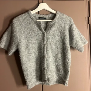 Grå stickad kofta från Gina Tricot - Helt oanvänd tröja ifrån ginatricot som är i bra skick! Är inte helt säker men den är köpt för ca 250-300! Skulle säga att den passar mellan xxs-xs!