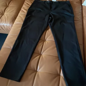 Svarta kostymbyxor med rak passform - Snygga svarta kostymbyxor med rak passform och klassisk design. Byxorna har diskreta fickor i sidorna och är tillverkade i ett slätt material som ger en stilren look. Perfekta för dig som gillar en clean och enkel stil.