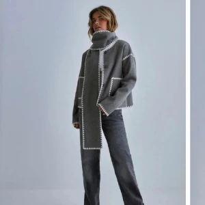 Grå polotröja med vita detaljer - Säljer en grå jacka med vita dekorativa sömmar längs kanterna. 