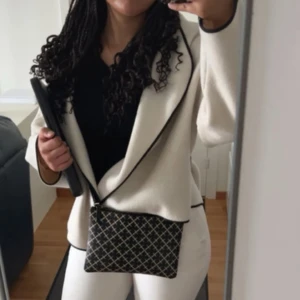 Beige omlott kavaj med svarta kanter - Säljer en beige kavaj med snygg omlott-design och svarta kontrastkanter. Kommer med matchande halsduk 