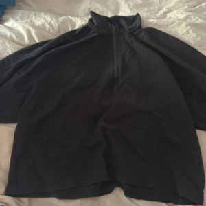 Svart half zip fleece från Aim'n - Svart fleece-tröja från Aim'n i storlek L. Tröjan har en hög krage och half zip-dragkedja framtill. Broderad Aim'n-logga på bröstet och långa ärmar. Perfekt för kyliga dagar och riktigt skön att mysa i.