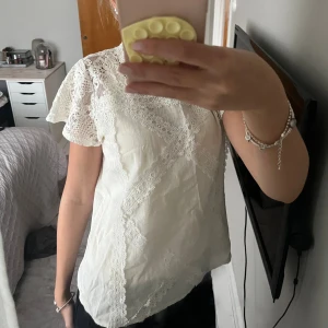 Vit spetsblus med volangärm - Supersöt vit blus med spetsdetaljer en liten gul fläck på men den syns inte 