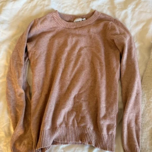 Ljusrosa stickad tröja från Vila - Supermjuk ljusrosa stickad tröja från Vila med rund halsringning och ribbade muddar vid ärmslut och nederkant. Perfekt för lager-på-lager och chill dagar. Enkel och stilren design som funkar till det mesta.