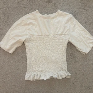 Vit topp  - Vit smockad topp från hm storlek S, slutsåld på hemsidan och använd ca 3ggr!