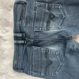 Diesel jeans bootcut blå denim - Snygga blå jeans från Diesel med bootcut passform. Jeansen har klassiska fem fickor, coola slitningar och detaljerade sömmar på bakfickorna. Tillverkade i robust denim med knappgylf och diskret Diesel-logga på läderpatch bak.