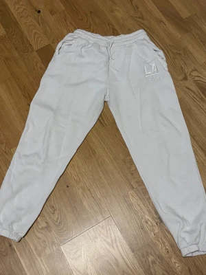 Vita mjukisbyxor  - Vita mjukisbyxor i storlek S. Byxorna har resår och snörning i midjan, muddar vid bensluten och fickor på sidorna. 