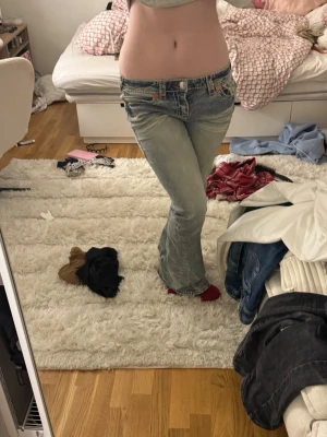 True Religion ljusblå bootcut jeans low waist  - Säljer ett par ikoniska ljusblå jeans från True Religion med röda kontrastsömmar och snygga detaljer på bakfickorna. Modellen har låg midja och bootcut-ben, köpta för 2200 i storlek M. Skriv vid frågor eller fler bilder ❤️