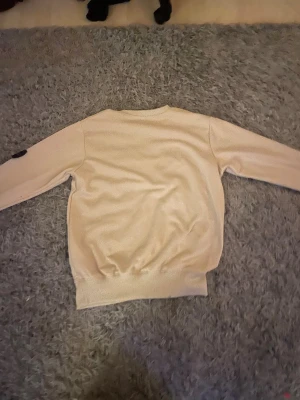 Beige Stone Island sweatshirt - Säljer en beige sweatshirt från Stone Island med klassisk patch på vänster ärm. Tröjan har rund halsringning, ribbade muddar och är tillverkad i mjuk bomull. Perfekt för dig som vill ha en clean och stilren look med streetwear-vibe.