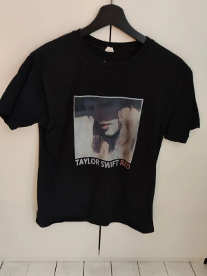 Taylor Swift Red Tour t-shirt  - Svart t-shirt med tryck framtill och tour dates på baksidan. Red Tour 2013 - Taylor Swift. Storlek står ej men jag skulle säga M. Köpt från Tradera ca 1 år sen, själv har jag bara använt den 2 gånger. Kan inte garantera att det är officiell merch, men tror det! 