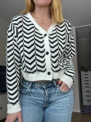 Svart/vit randig kofta, storlek S - En randig kofta med knappar i svart och vit. Storlek S.  Mjuk och skön! Aldrig använd.  Längd: 46 cm Axel: 54 cm Byst: 101 cm
