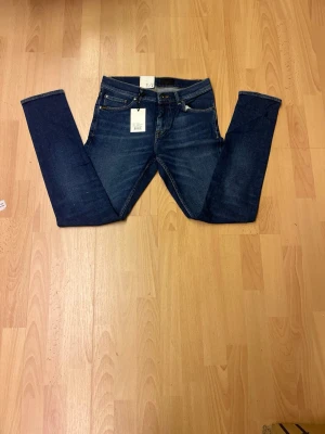 Blå slim fit jeans från Tiger of sweden W29 L32 - Snygga blå jeans från T/J i slim fit-modell med klassisk femficksdesign och gul kontrastsöm. Jeansen har en mörk tvätt och läderpatch bak i midjan. Perfekta för dig som gillar en smalare passform och stilren look.