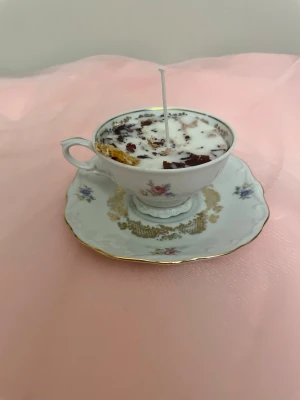 Doftljus i en vit tekopp med blommor i doft utav vanilj nr 6 - Det här ljuset är gjort av återanvändbara material. Tekoppen är köpt secondhand och stearinet är från kyrkor som tänkte slänga det. Det här ljuset har en svag doft utav vanilj, så känsliga även kan använda det. Det här ljuset har även torkade blommor och torkad apelsin på som dekoration. Det finns fler av denna design på hemsidan om man vill köpa sets. 