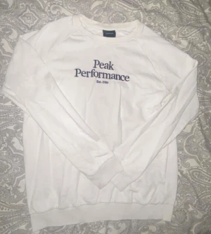 Vit Peak Performance sweatshirt - Säljer en vit sweatshirt från Peak Performance med svart logga ganska schyst inga märken osv jättechill bekväm tröja, Storlek 170 