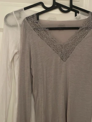 2 långärmade toppar Intimissimi S - Säljer två långärmade toppar från Intimissimi i storlek S. En är ljusbeige med spetsdetaljer vid v-ringning och ärmslut, den andra är vit och enkel. Båda är tunna och supermjuka, tillverkade i en kashmirblandning. Perfekta att styla lager på lager eller som de är. En för 279, båda för 479kr. Supersnygga båda två! Skriv för fler bilder eller frågor om plaggen 🥰